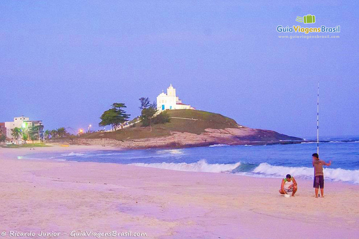 Imagem de pai e filho pescando no fim de tarde na Praia da Vila.