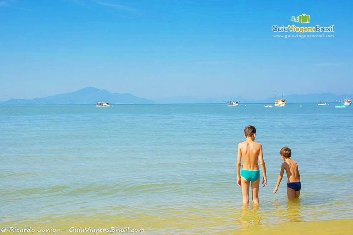 Imagem de pai e filho entrando nas águas do mar.