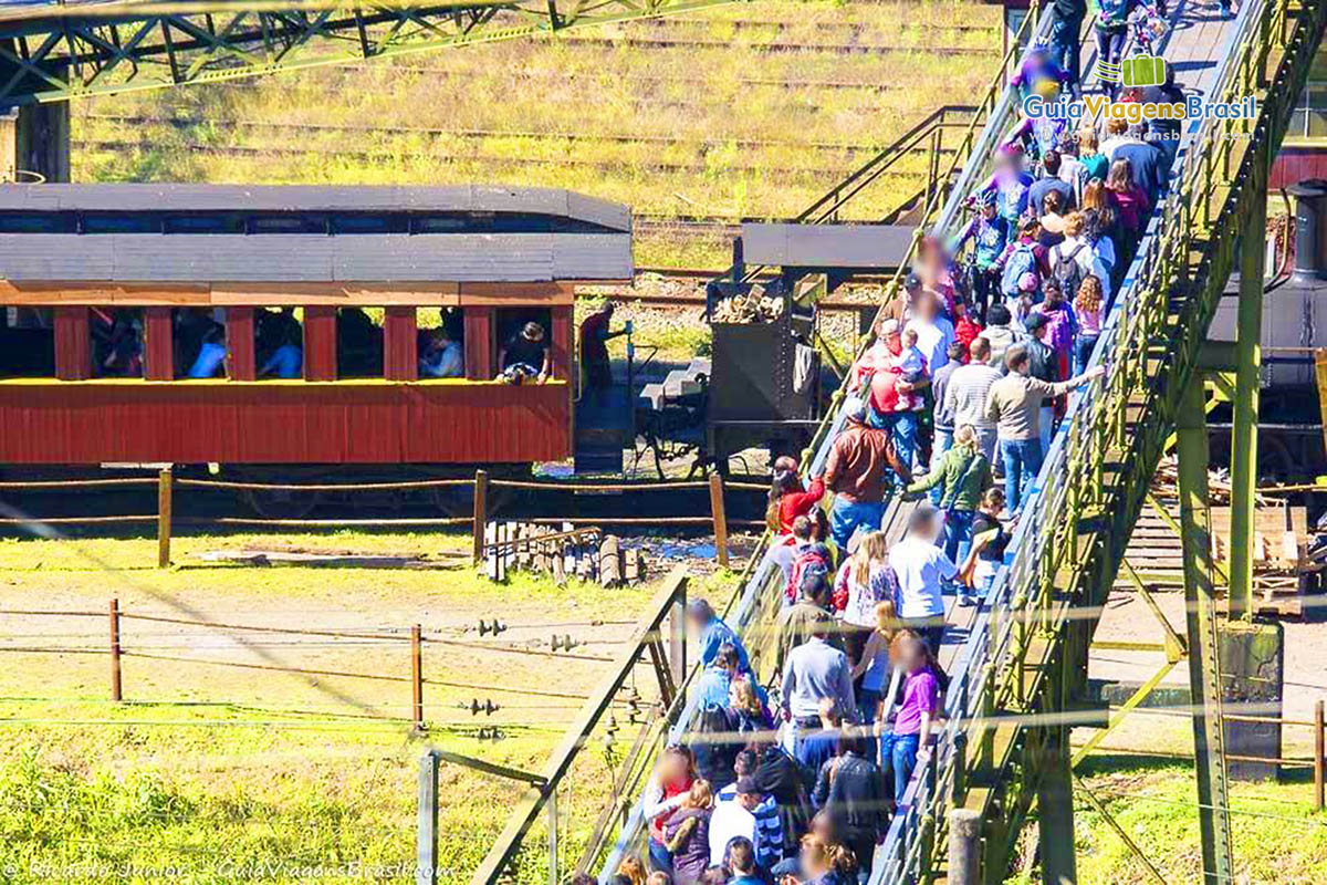 Imagem de vários turistas passando pela passarela em direção a Estação de Trem.