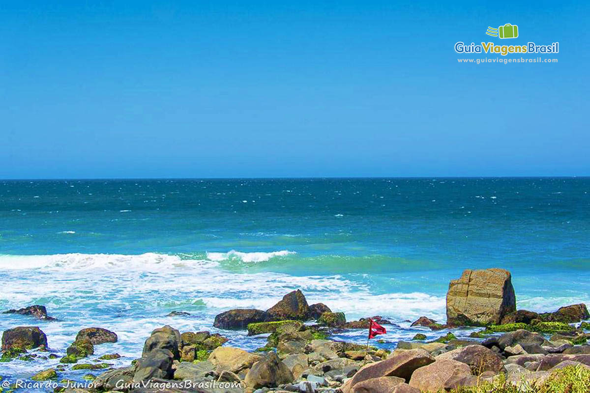 Imagem do mar batendo nas pedras da praia.