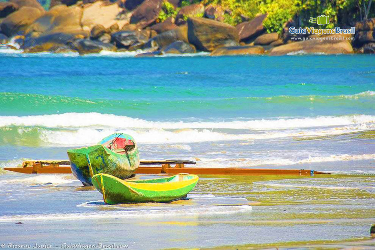 Imagem de pequenos barcos com remo na beira da praia, em Ilhabela.