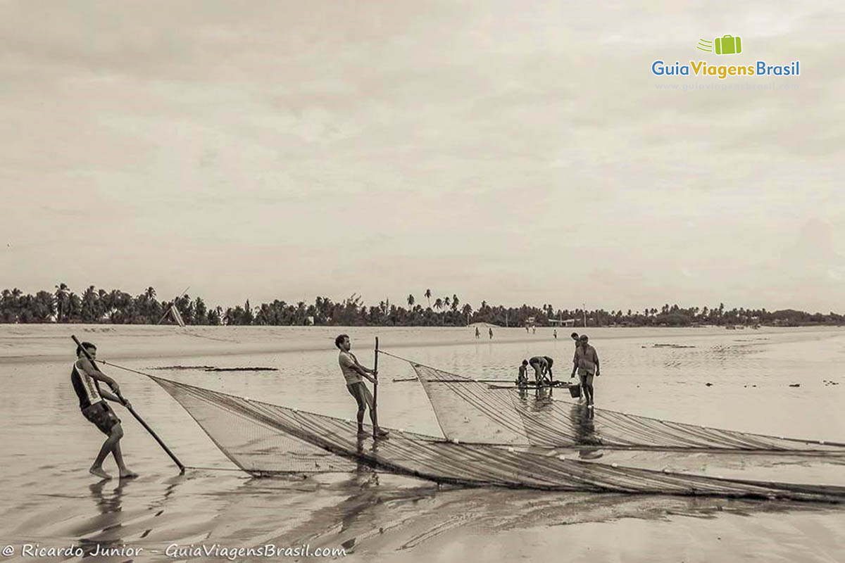 Imagem de pescadores puxando a rede na Praia do Cardeiro.