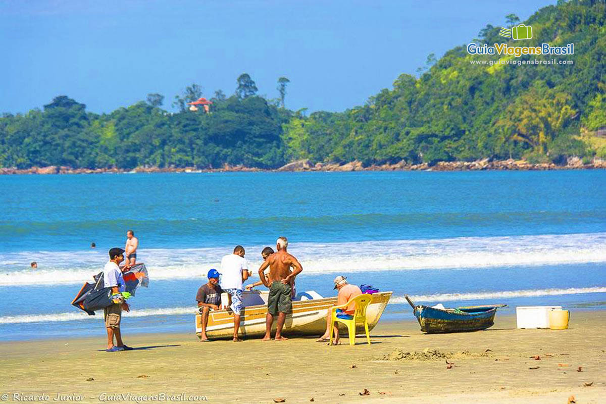 Imagem de pescadores em torno do barco nas areias da Praia Maranduba.