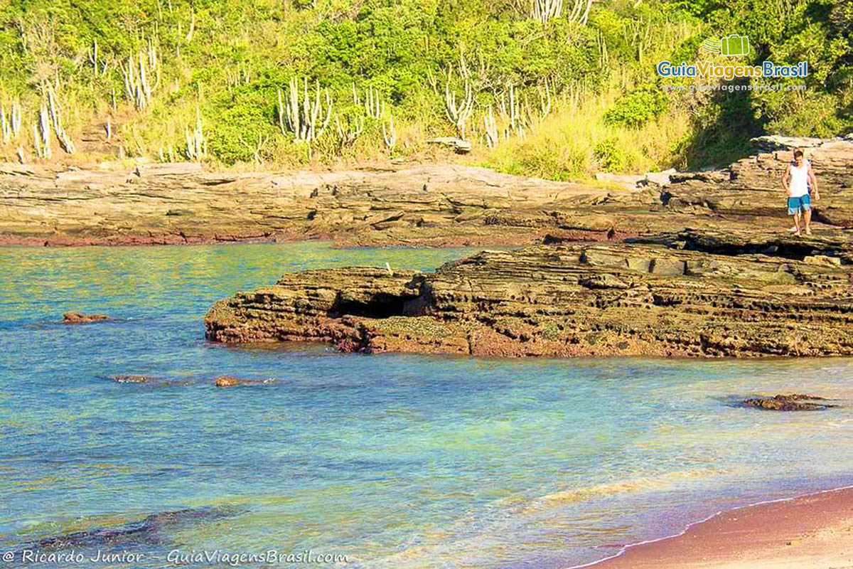 Imagem de uma pessoa andando sobre as pedras da Praia do Forno.