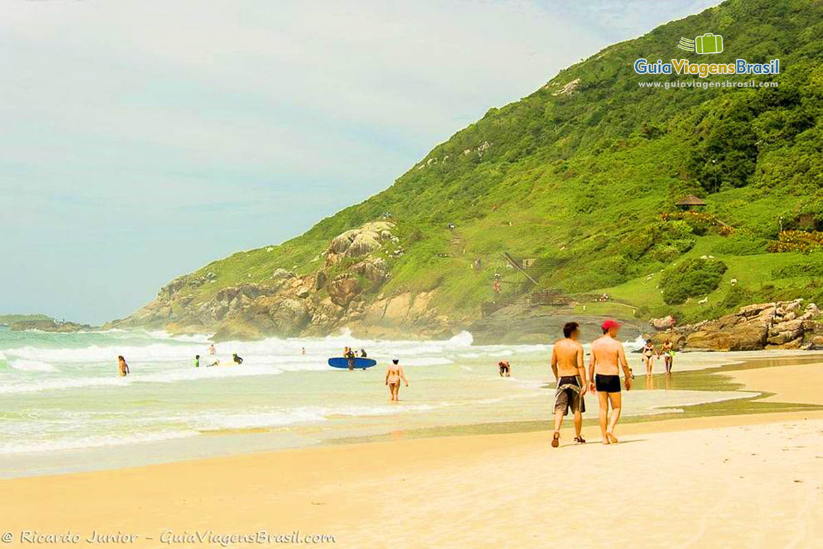 Imagem de duas pessoas caminhando nas areias da Praia do Santinho.