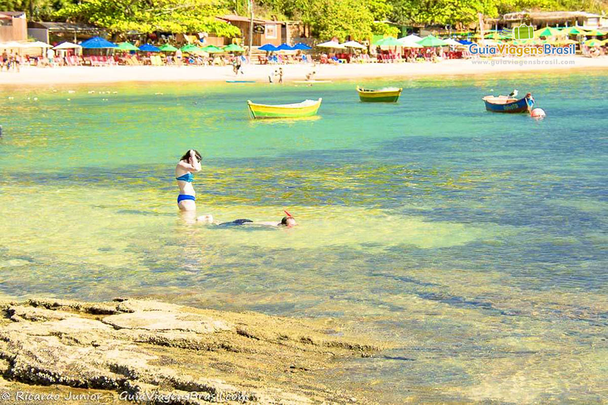 Imagem de duas pessoas mergulhando nas águas cristalinas da praia.