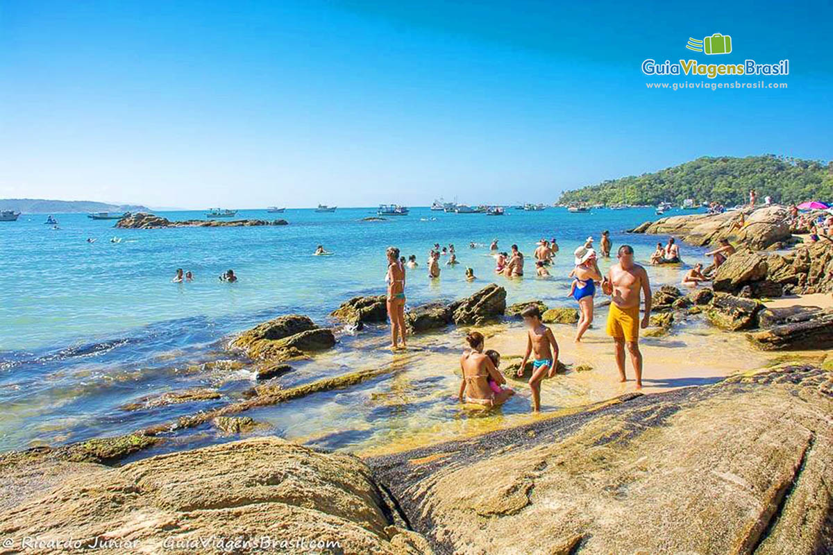 Imagem de pessoas nas pedras, curtindo o belo dia.