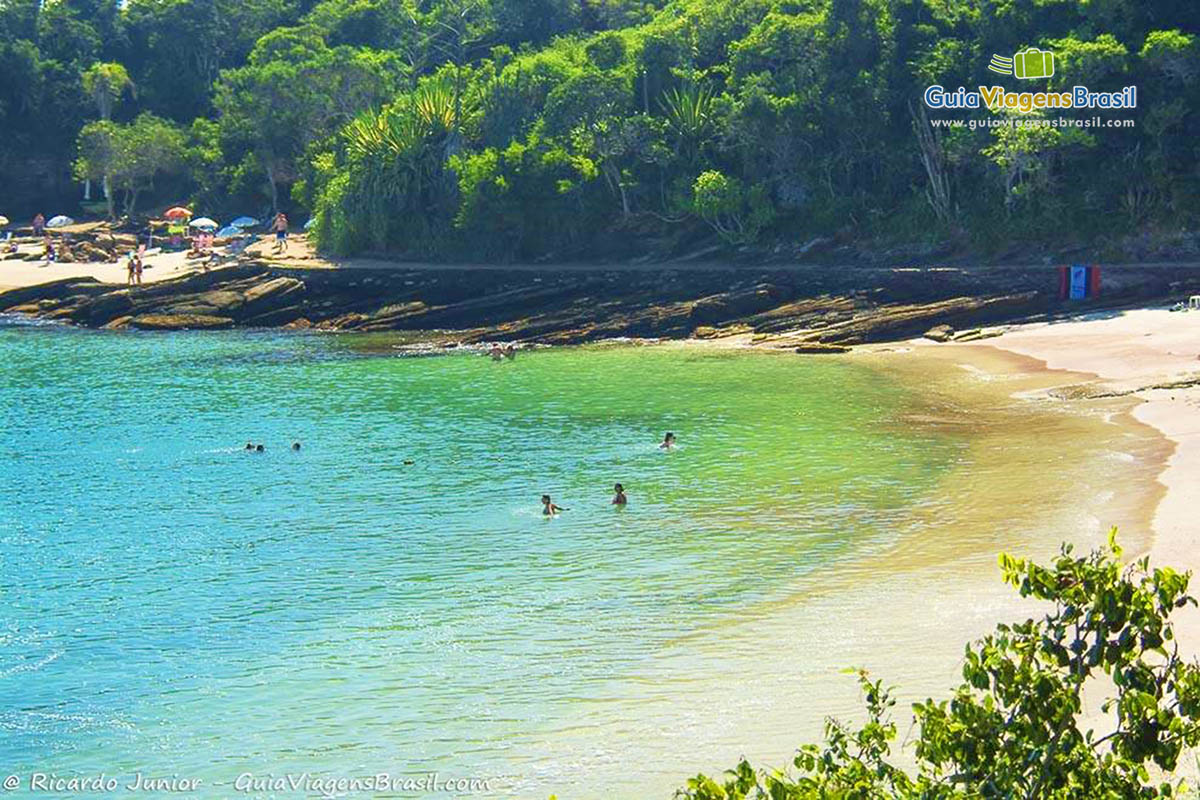 Imagem do mar e pessoas nas águas maravilhosas da belíssima praia.