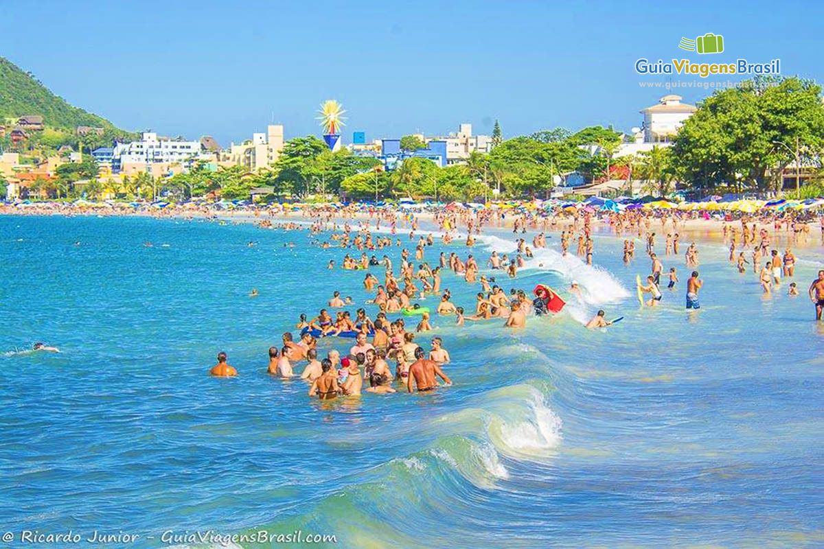 Imagem de várias pessoas no mar aproveitando o dia de sol.