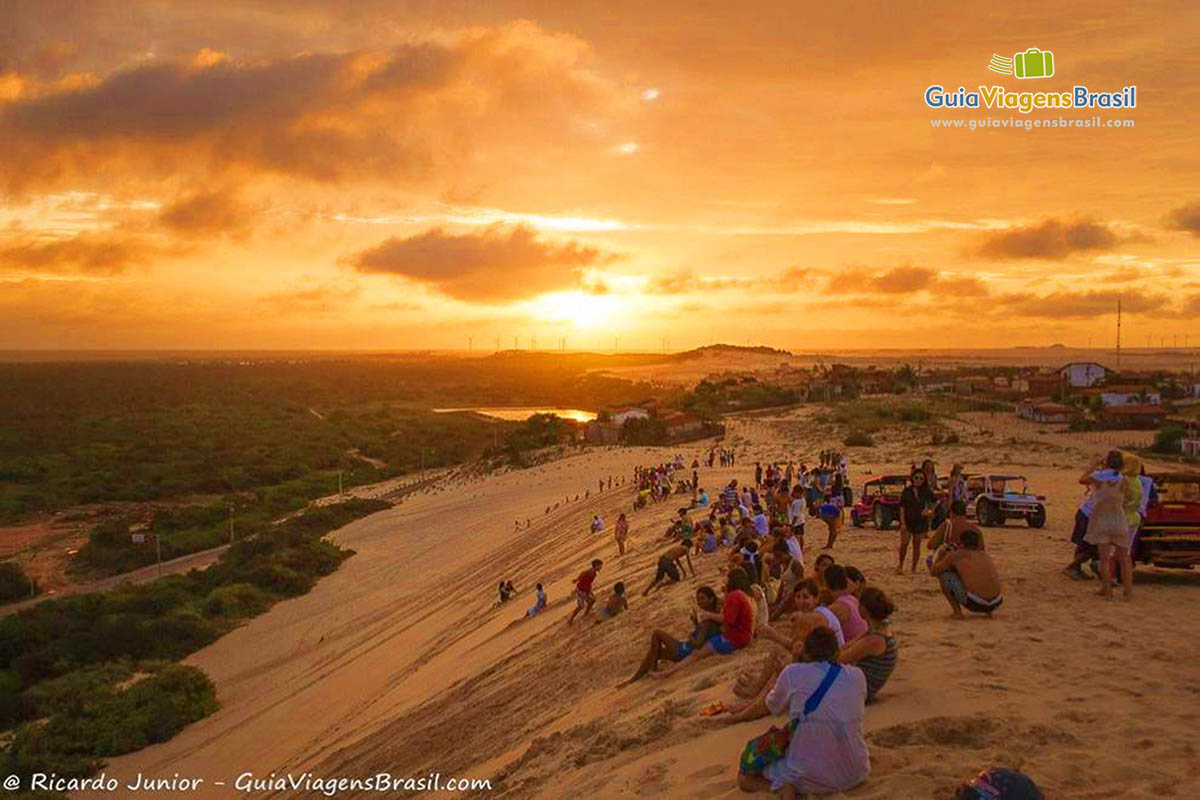 Imagem do céu alaranjado com turistas admirando o lindo fenômeno da natureza.