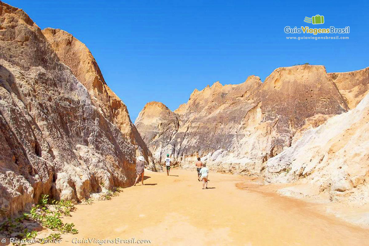 Imagem de turistas caminhando por entre as falesias coloridas de Beberibe.