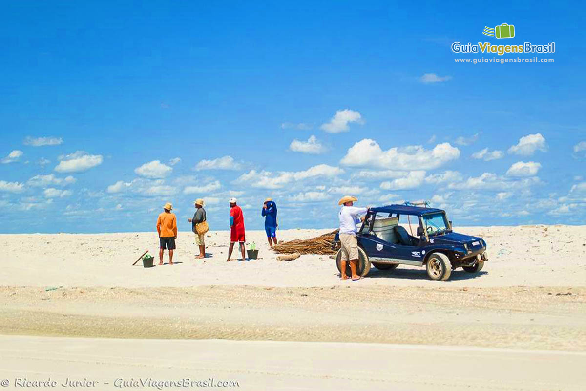 Imagem de pessoas se preparando para praticar kitesurfe, na Praia Deserta.