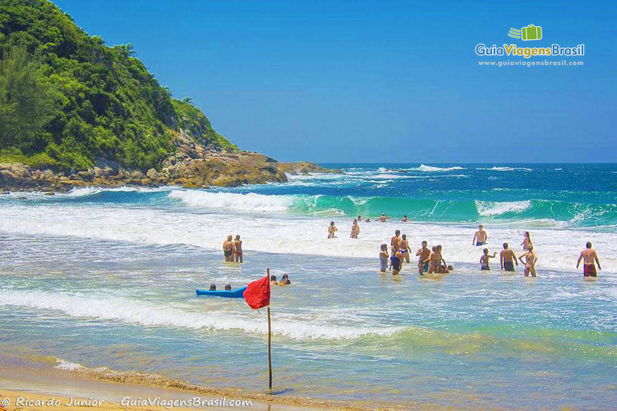 Imagem de bandeira vermelha na beira da praia.