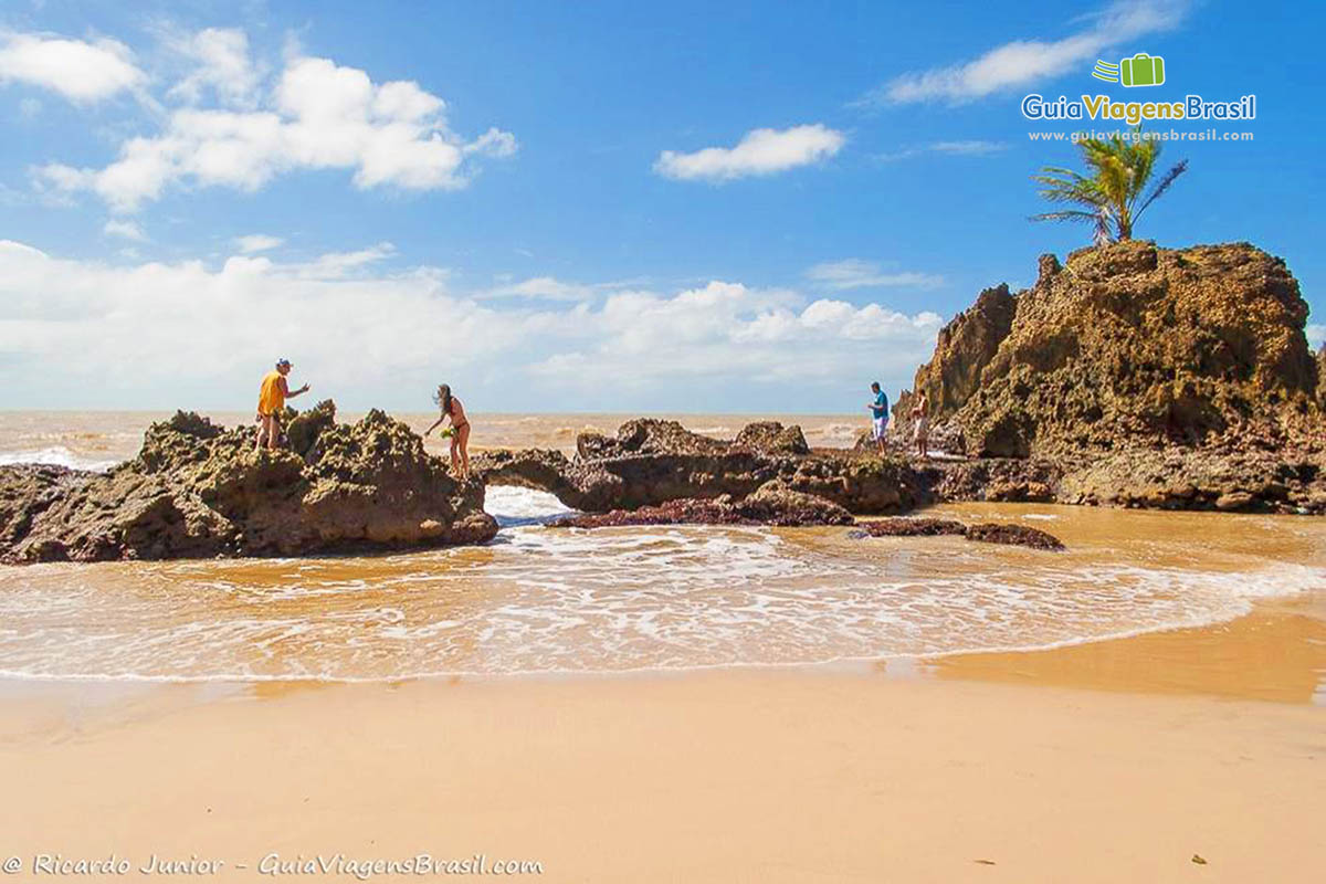 Imagem de turistas nas pedras da Praia Tambaba.