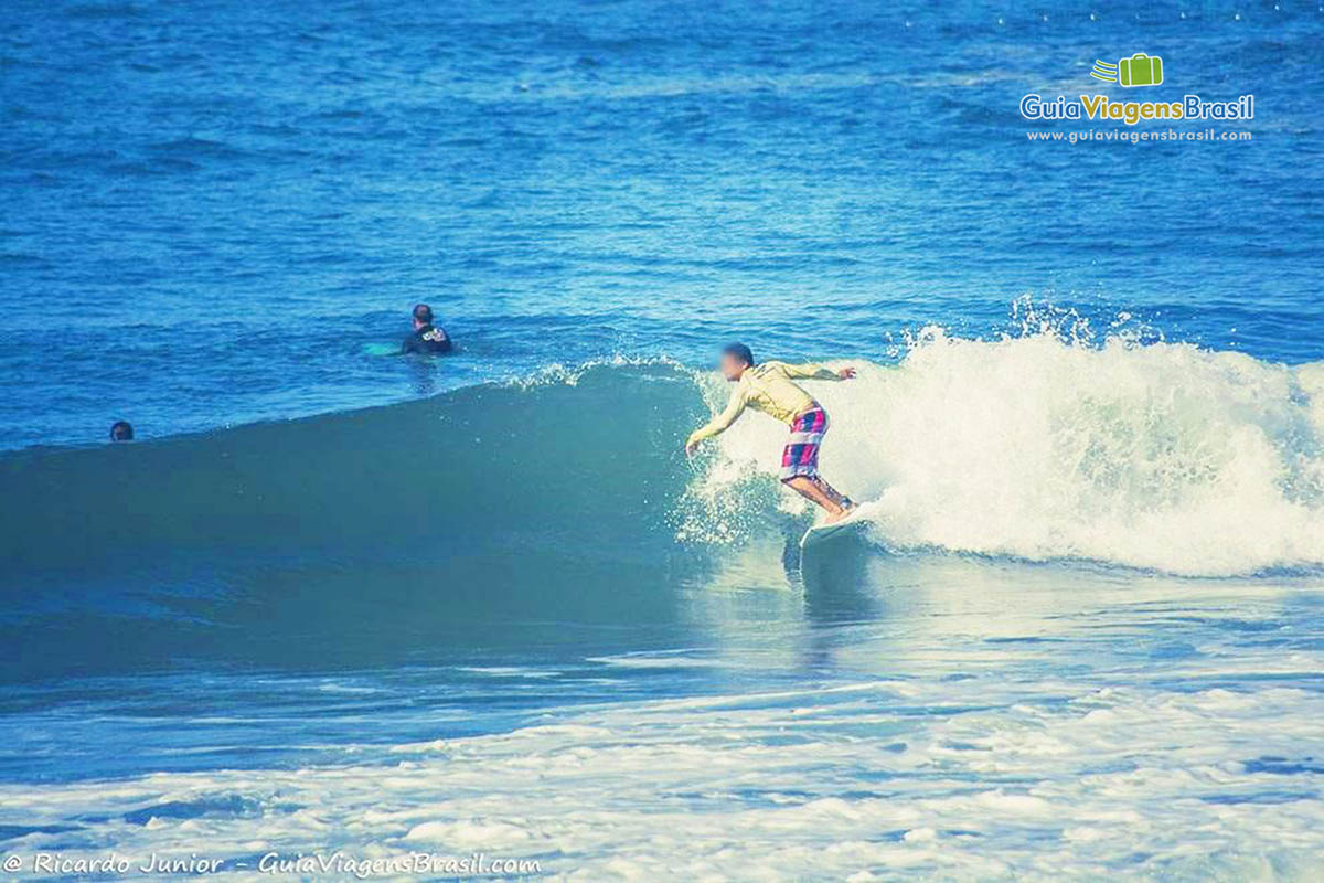 Imagem de surfista pegando onda na praia.