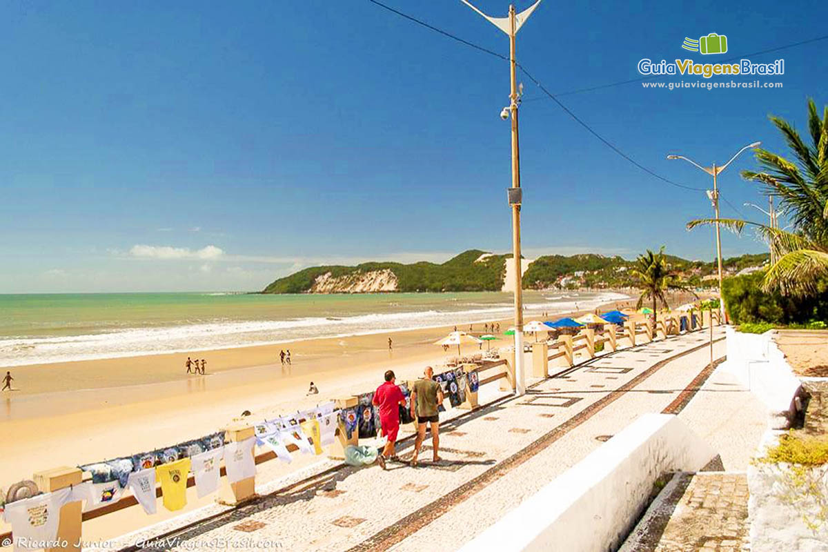 Imagem de camisas sendo vendidas no calçadão da Praia Ponte Negra.