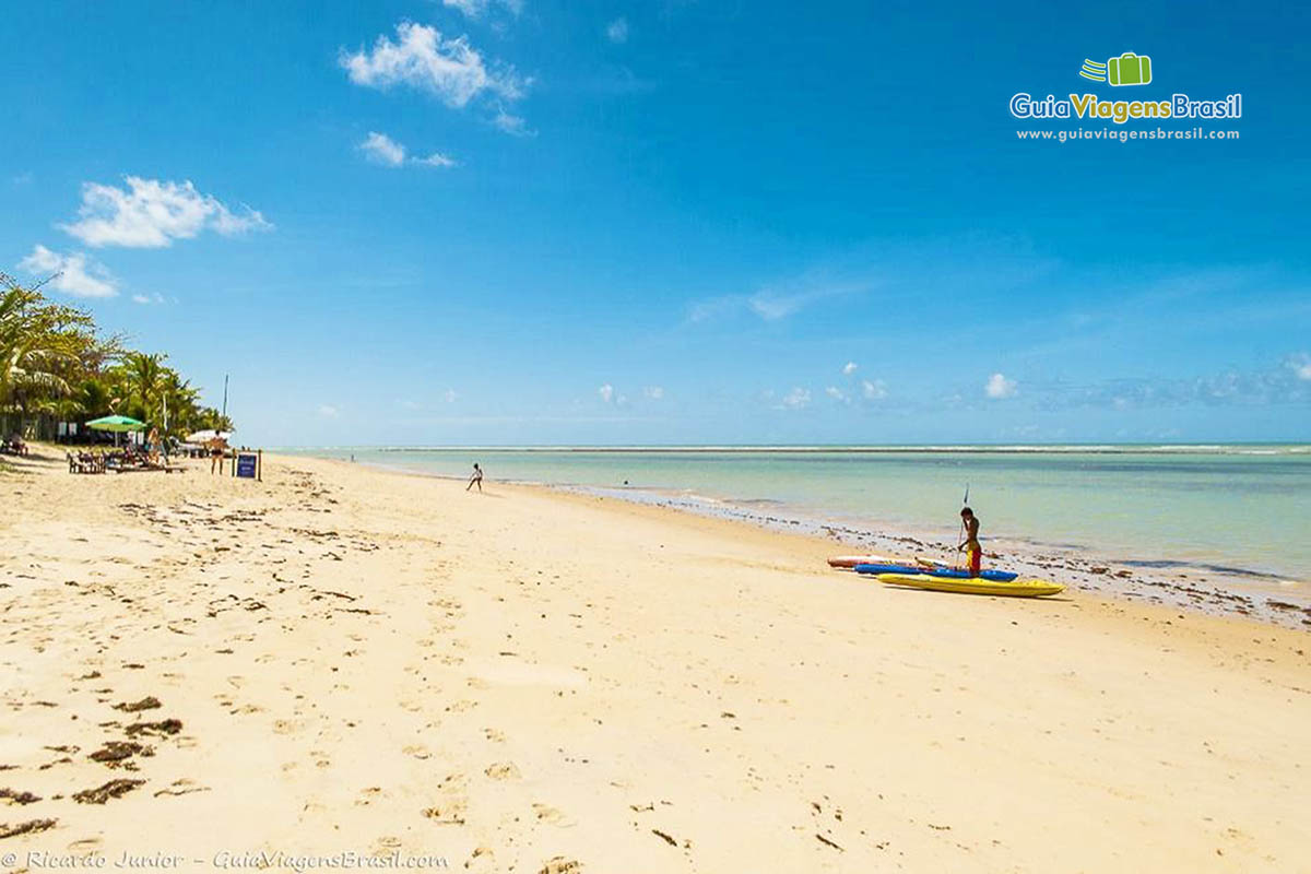 Imagem de caiaques na beira da praia e ao fundo o mar maravilhoso.