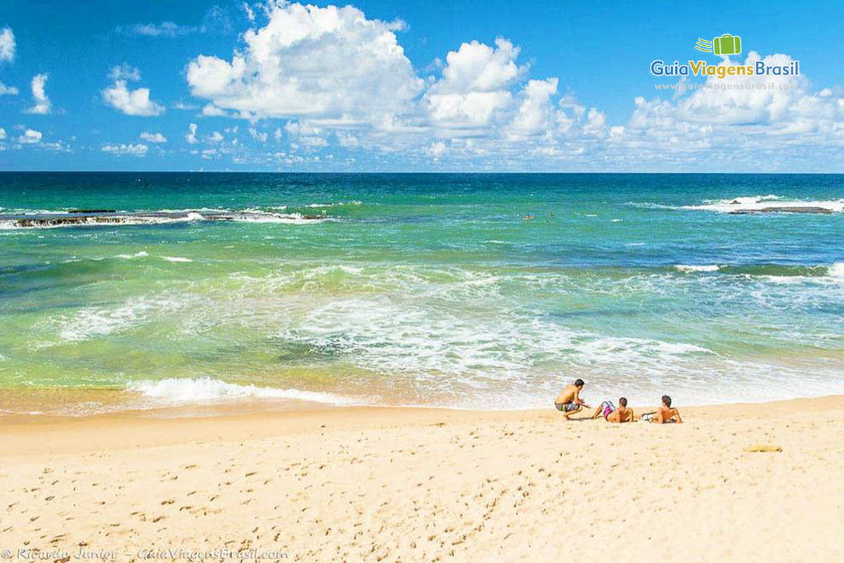 Imagem de três amigos sentados na beira da linda Praia Arembepe.