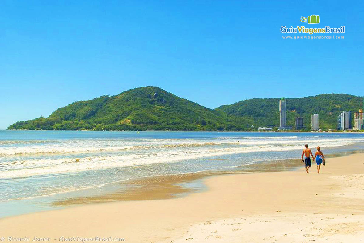 Imagem de casal caminhando na beira da praia.