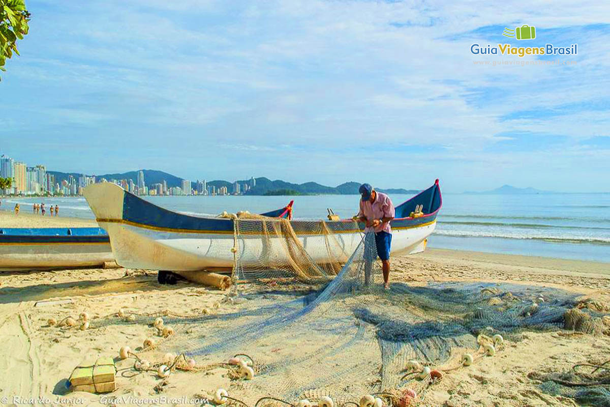 Imagem de pescador arrumando a rede para pescar.