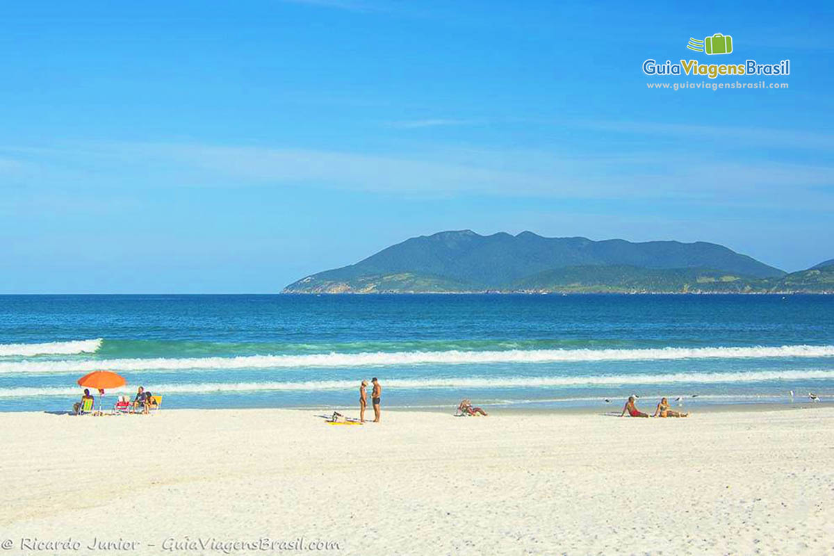 Imagem de amigos e casais curtindo o sol na Praia das Dunas.