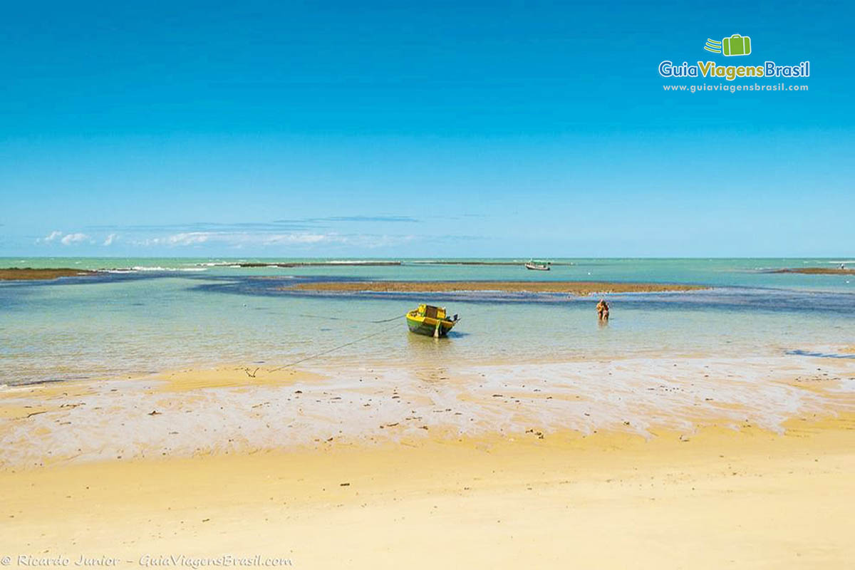 Imagem de turistas e barcos no mar maravilhoso da Praia do Espelho.