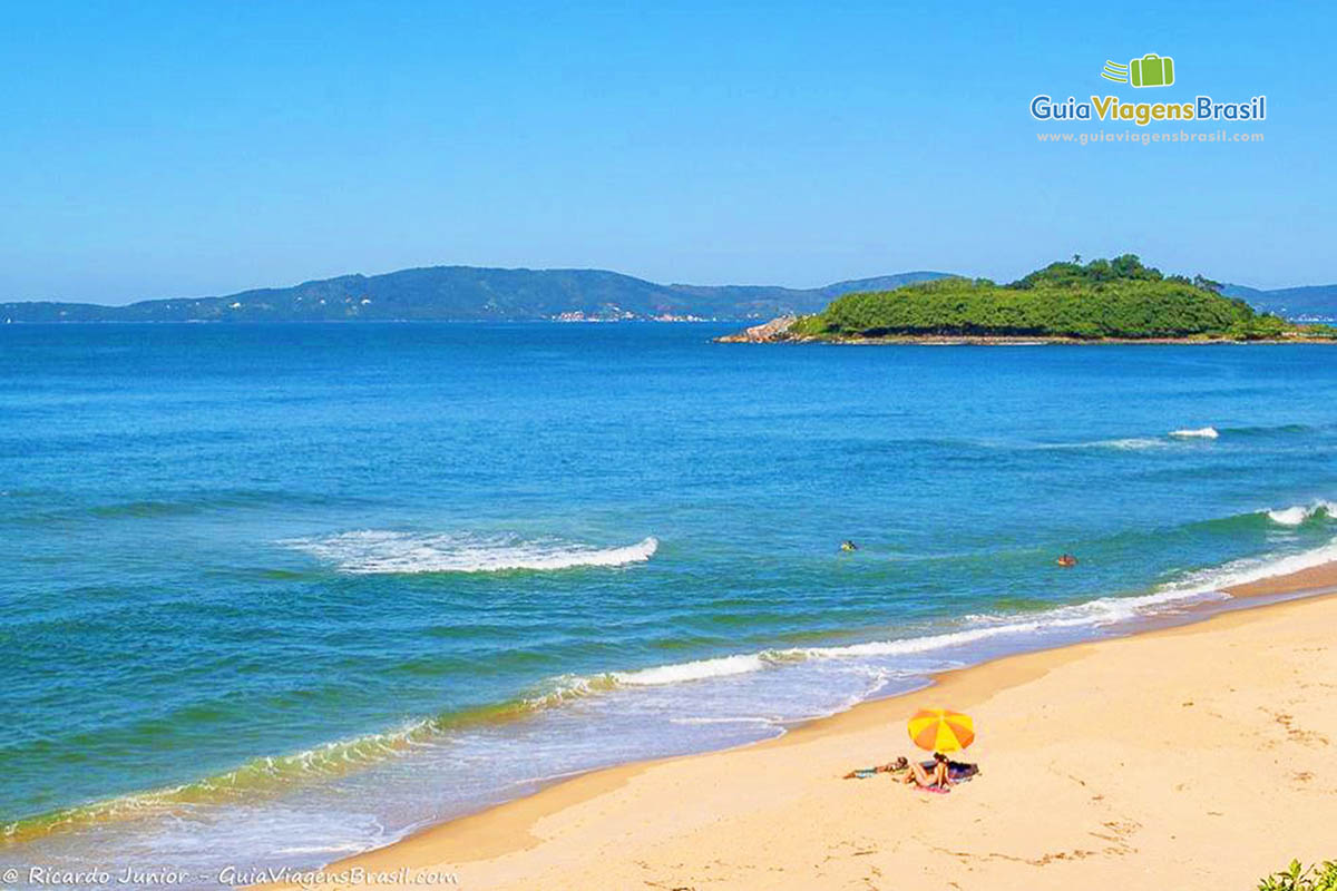 Imagem de turistas com guarda sol na Praia do Plaza.