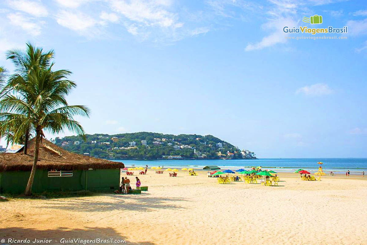 Imagem de quiosque e turistas nas areias da Praia da Enseada.