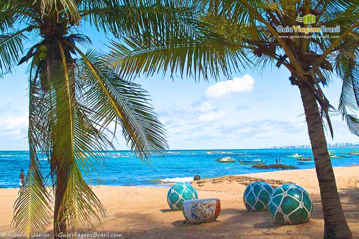 Imagem de coqueiros e linda decoração de cerâmica nas areias da Praia Itapuã.
