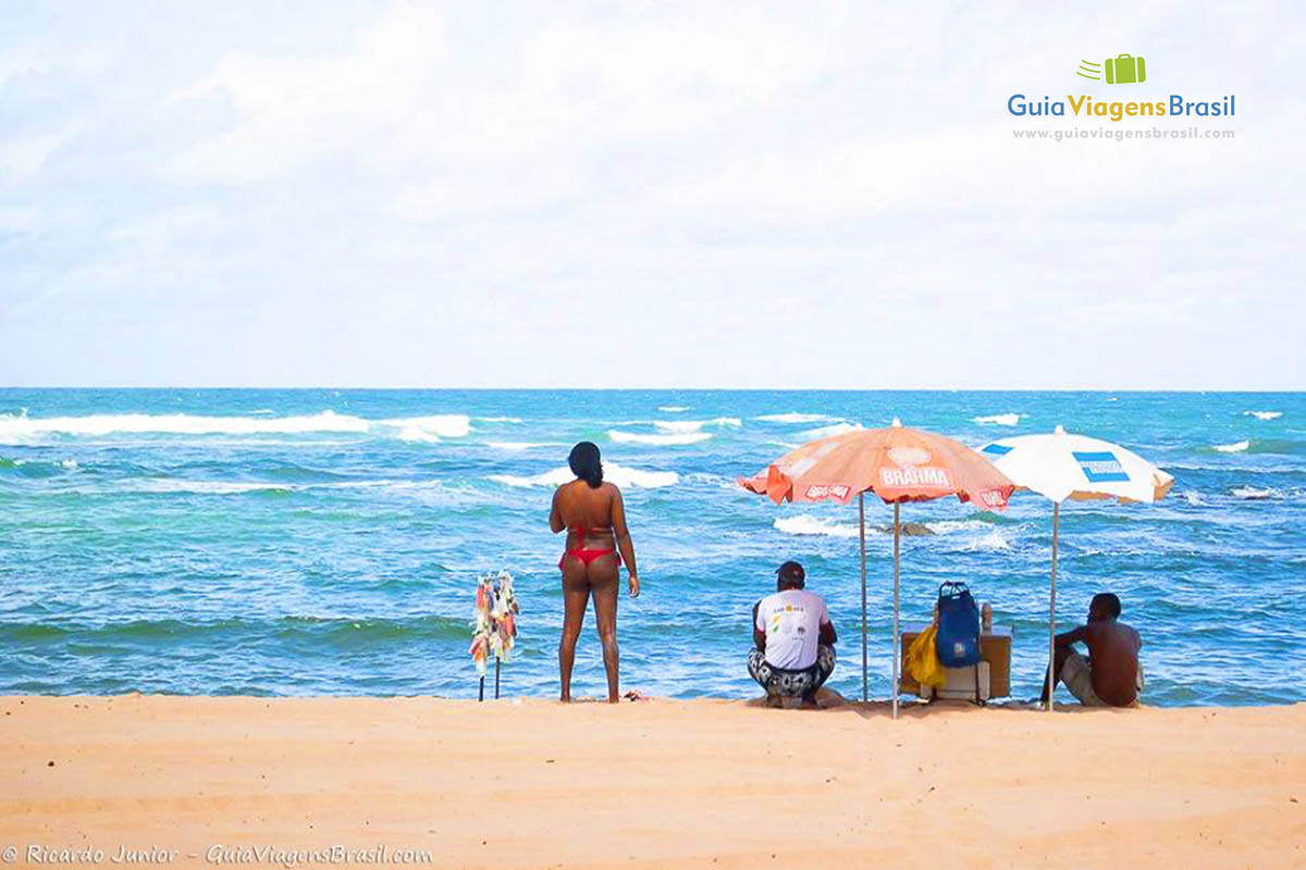 Imagem das areias claras e ao fundo o belo e charmoso farol da Praia Itapuã.