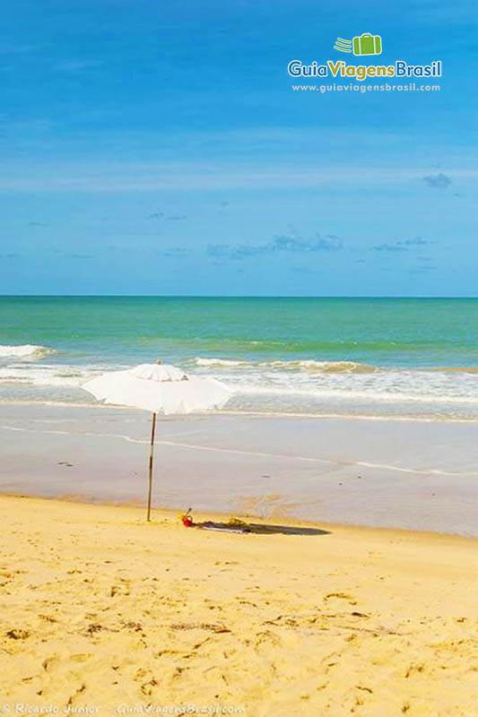 Imagem de guarda sol branco na beira da Praia Nativos.