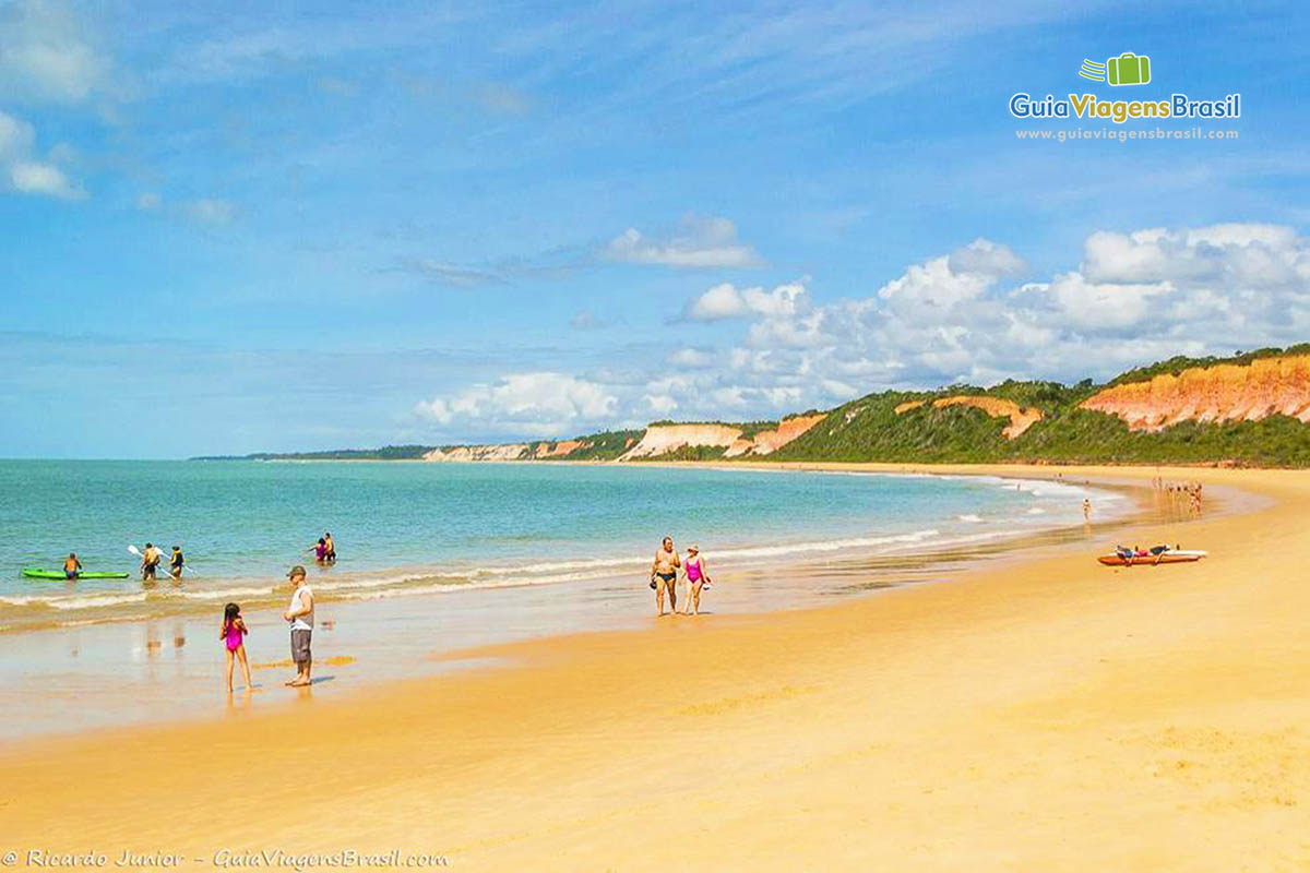 Imagem de pessoas na beira da praia e caiaque no mar.