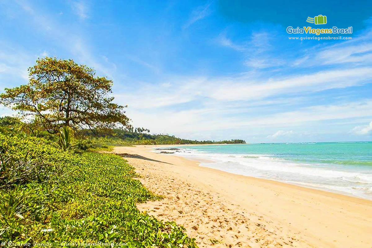 Imagem da praia com a maré alta com faixa de areia pequena.