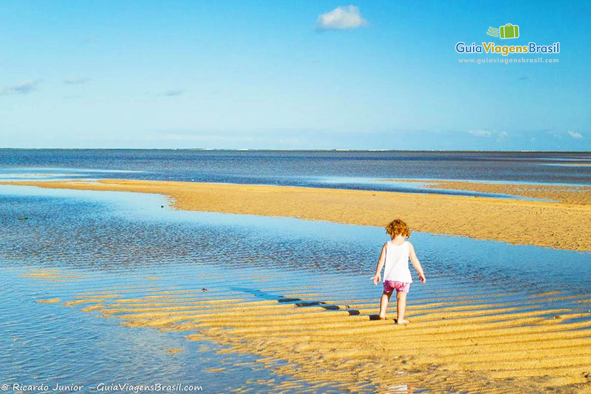 Imagem de uma criança andando nas águas na Praia Tatuamunha.