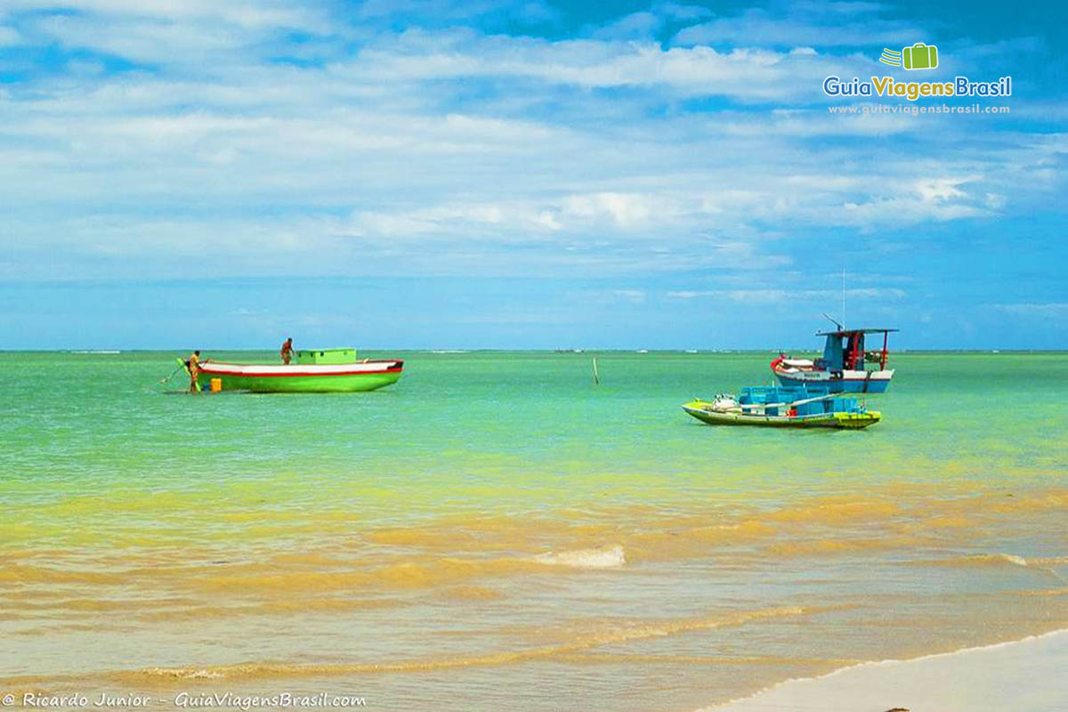 Imagem de barcos nesta mar azul esverdeado.