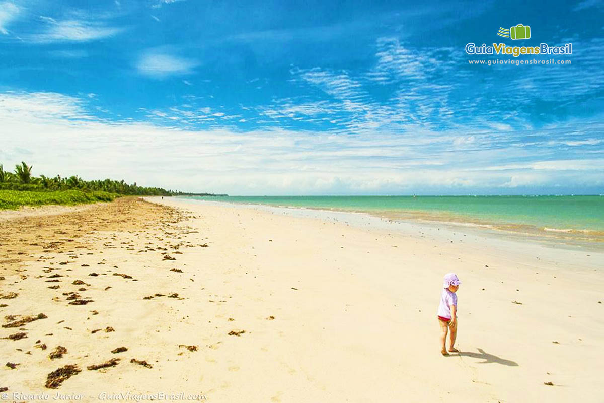 Imagem de uma crianças andando nas areias da belíssima praia.