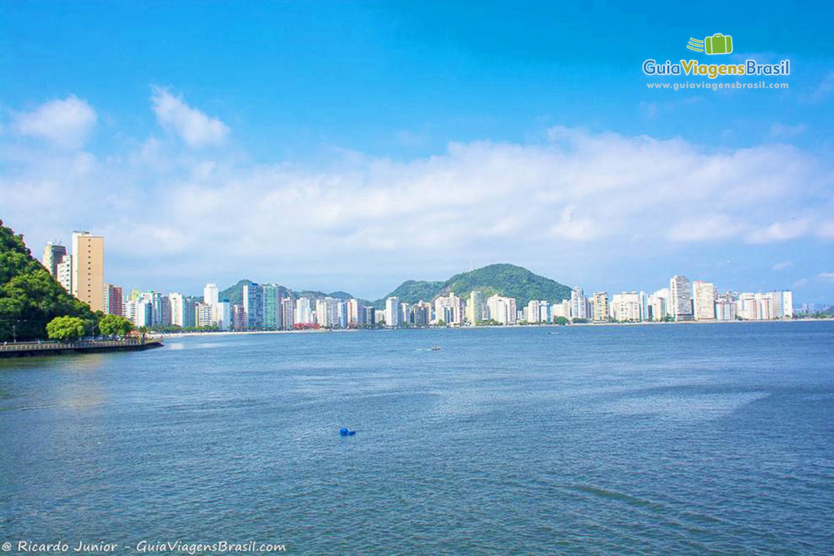 Imagem do mar azul e ao fundo os prédios da orla da praia.