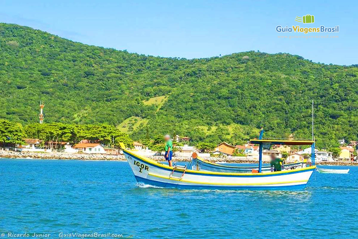 Imagem de pescadores em seus barcos em alto mar.