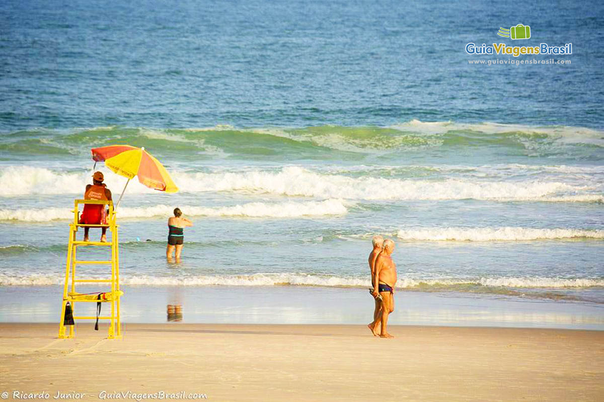 Imagem de salva vidas sentado em seu posto olhando para o mar.