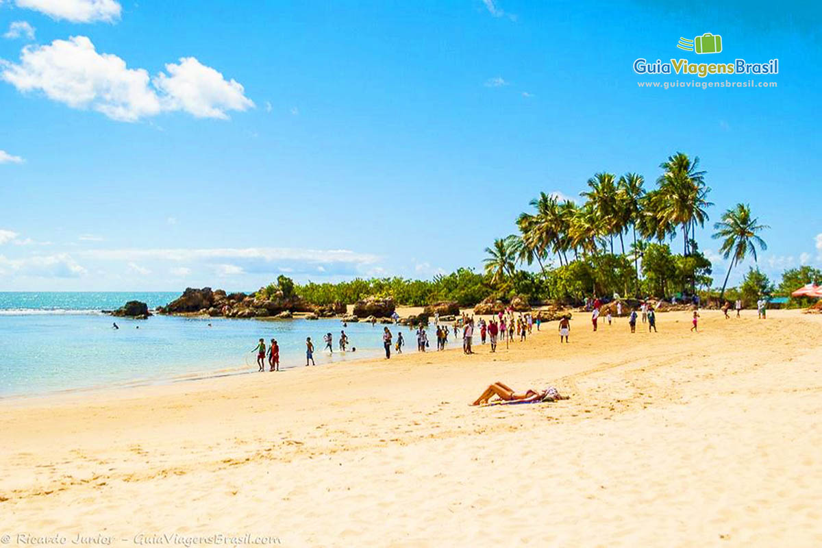 Imagem da praia repleta de turistas adolescentes, praia muito badalada.