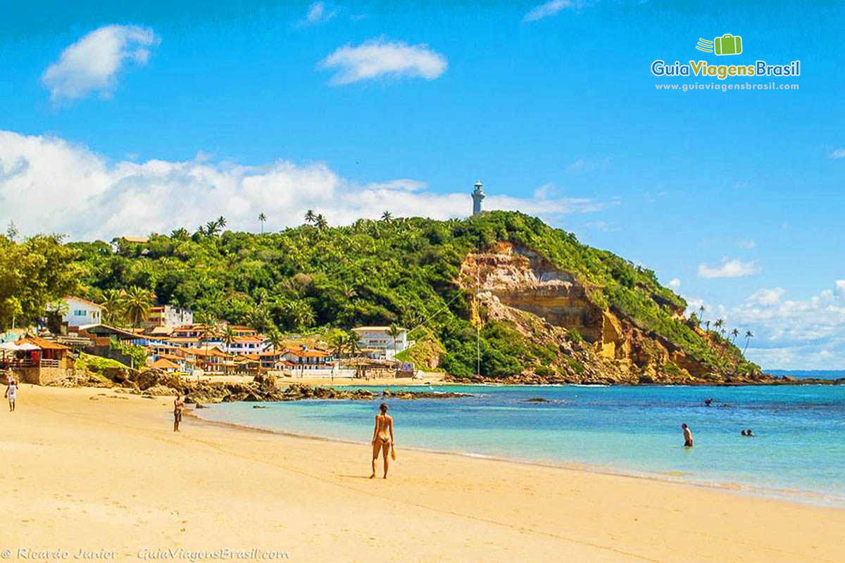 Imagem de turistas jogando frescobol na beira da Segunda Praia.