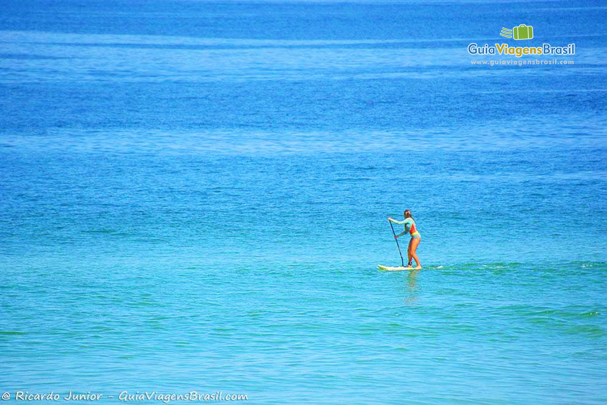 Imagem de pessoas no mar praticando o stand up paddle.