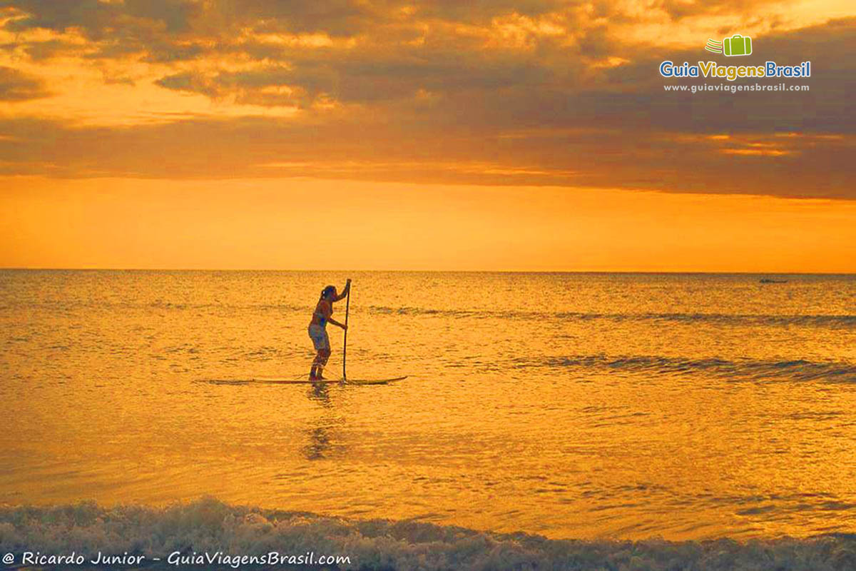 Imagem de pessoa praticando stand up paddle.