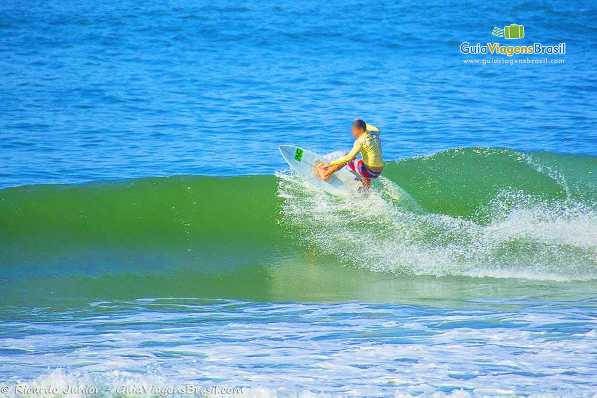 Imagem de surfista fazendo manobras na praia.