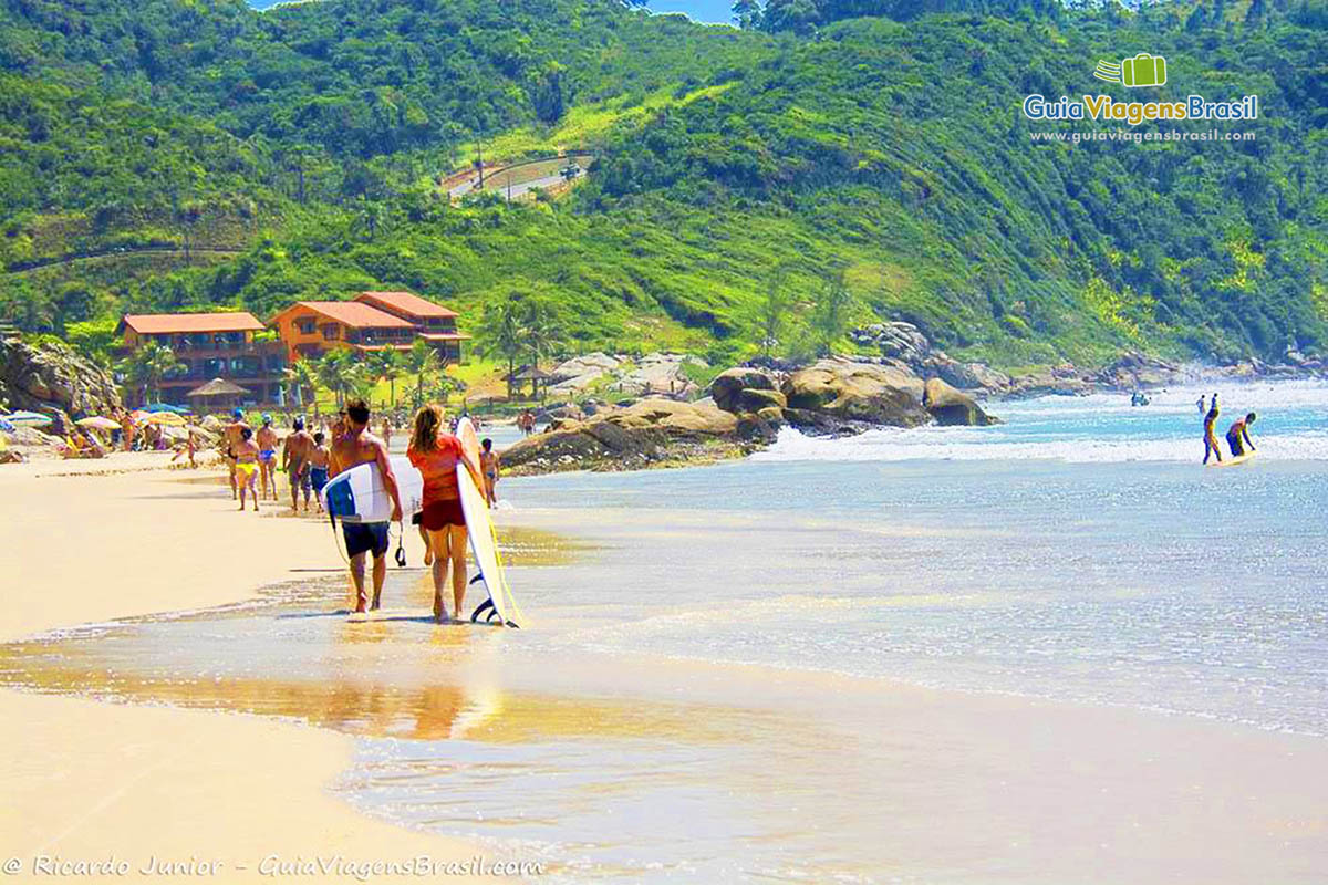 Imagem de surfistas com suas pranchas na areia da praia.