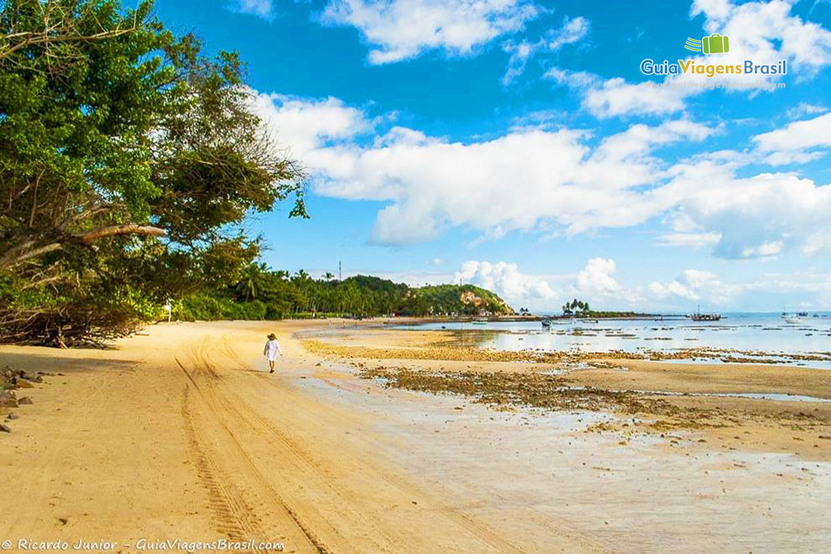 Imagem de turistas caminhando pelas areias da linda praia.