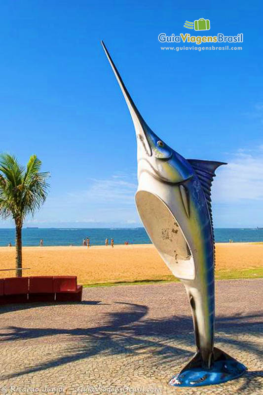 Imagem do orelhão em formato de tubarão na orla da praia.