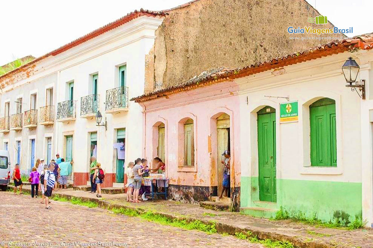 Imagem de moradores vendendo coisas na porta de suas casas ao visitantes da cidade.