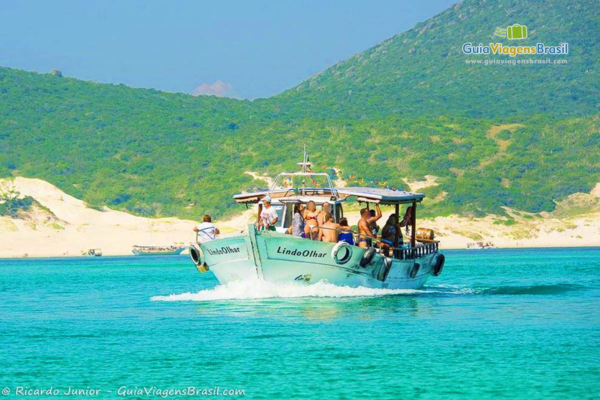 Imagem de frente do barco com turistas indo embora da maravilhosa praia.