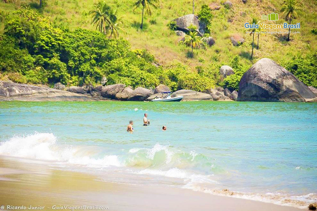 Imagem de turistas nas águas da praia.